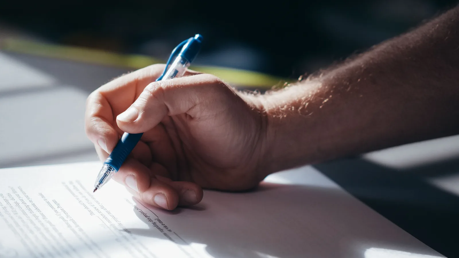 Hands signing a proposal document at a desk