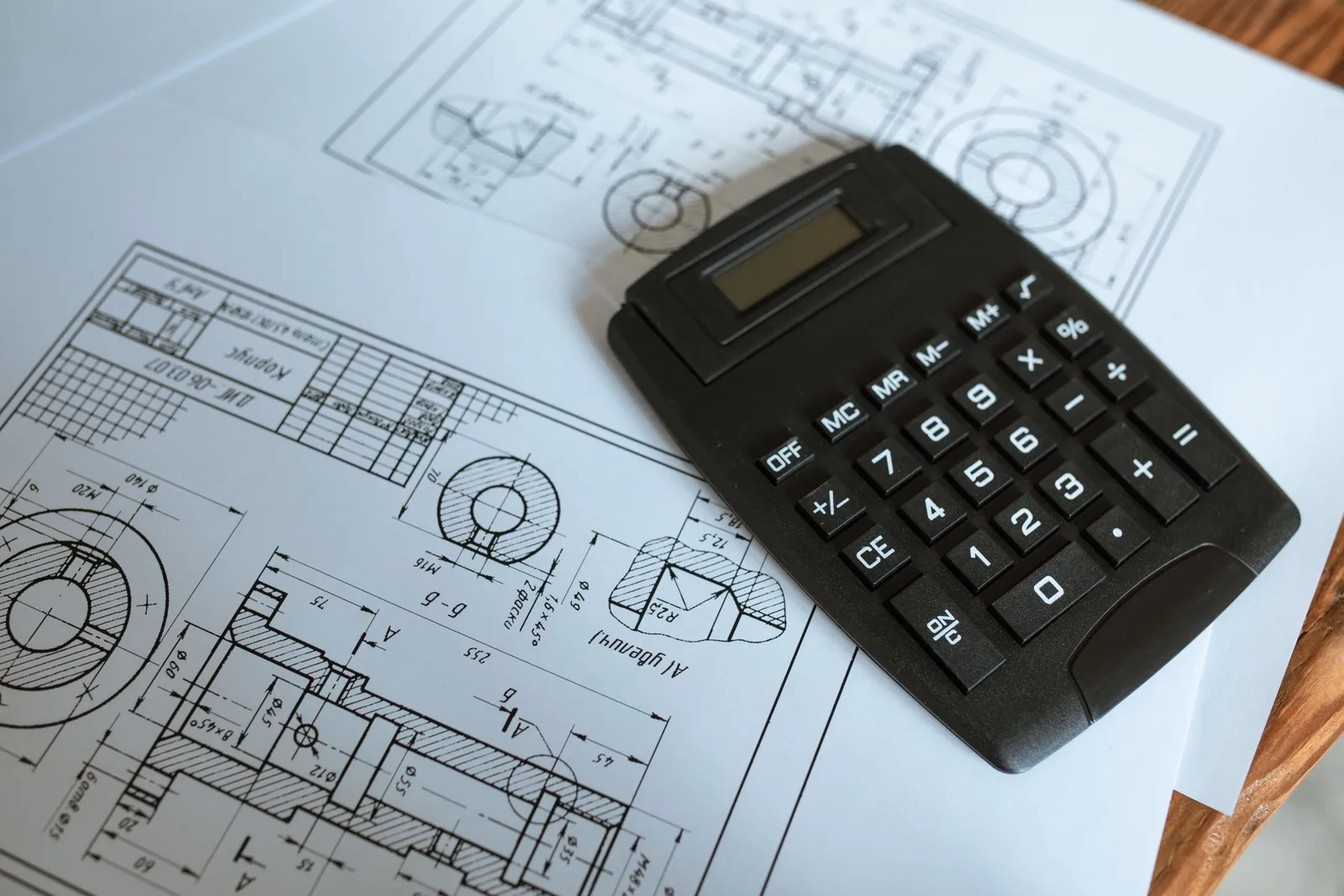 Estimator reviewing architectural drawings with a calculator and takeoff sheets