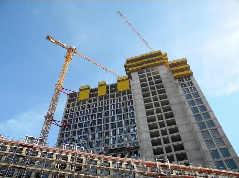 High-rise building under construction with a tower crane and perimeter scaffolding
